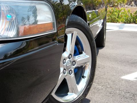 2003 Mercury Marauder - Close-up of a black 2003 Mercury Marauder's front wheel, its chrome rim and bright blue brake caliper.