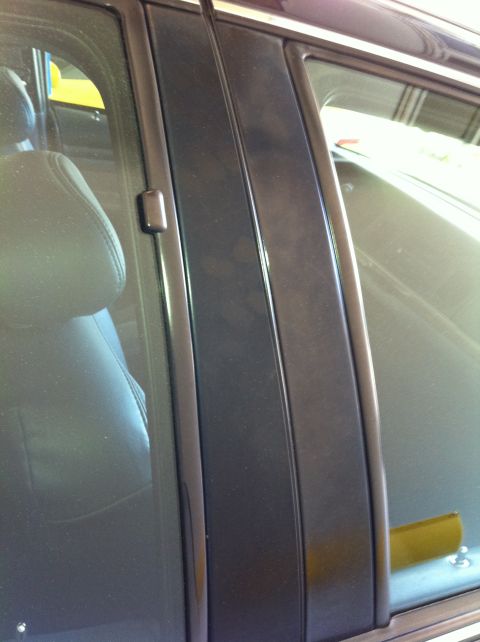 1999 Ford Crown Victoria - Close-up of a car's B-pillar shows smudges and interior reflections, with no clear year identification.