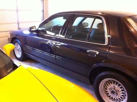 1999 Ford Crown Victoria - Side view of a dark blue 1999 Ford Crown Victoria sedan parked indoors.