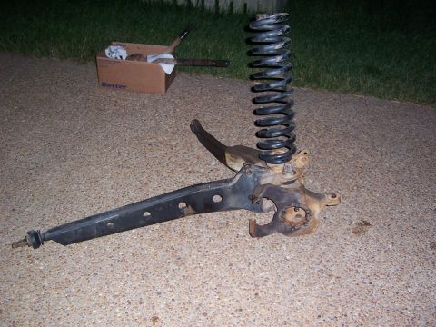 1992 Ford Bronco - A disassembled suspension component, including a coil spring and control arm, rests on a concrete surface.