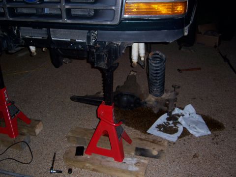 1992 Ford Bronco - The front suspension of a Ford truck is disassembled and supported by jack stands for repair.