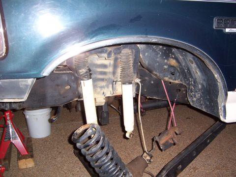 1992 Ford Bronco - The rear suspension of a 1992 Ford Bronco is shown with the coil spring and shocks removed, supported by jack stands.