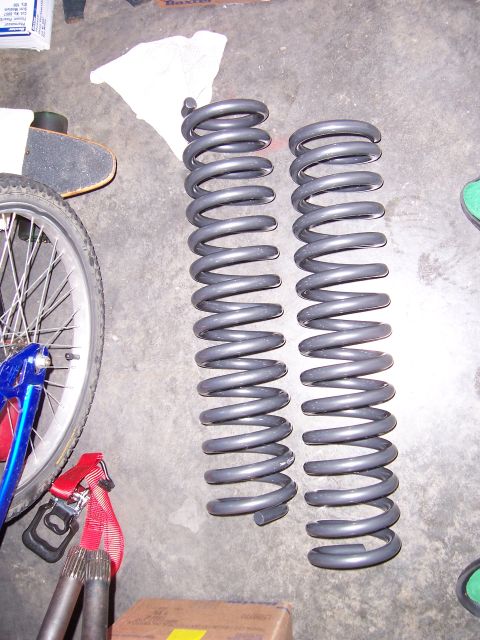 1992 Ford Bronco - Two suspension coil springs are shown on a garage floor, alongside a bicycle wheel and a skateboard.
