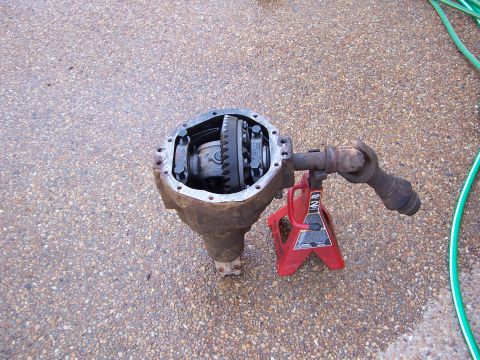 1992 Ford Bronco - Differential housing with gears visible, resting on a jack stand on a paved surface.