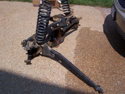 1992 Ford Bronco - Disassembled vehicle suspension components are shown resting on a paved surface with grass in the background.