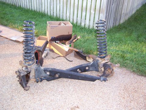 1992 Ford Bronco - Disassembled front suspension parts are laid out on the ground next to cardboard boxes.