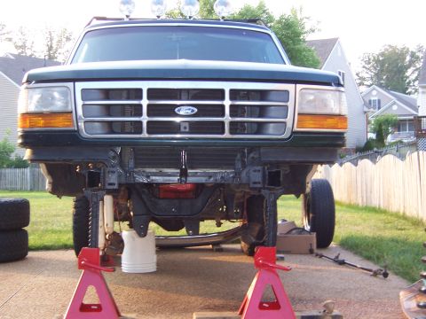 1992 Ford Bronco - Front view of a 1992 Ford Bronco with its grille and bumper removed, elevated on jack stands for maintenance.