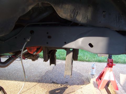 1992 Ford Bronco - Vehicle's undercarriage, showing frame and suspension parts, supported by red jack stands.