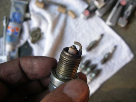 1990 Ford Bronco - A close-up view of a spark plug being held, with several other spark plugs visible in the background on a white cloth.