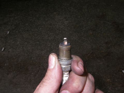 1990 Ford Bronco - Close-up of a spark plug being held by fingers.