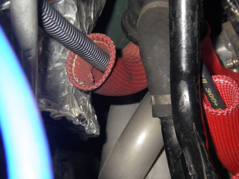 1990 Ford Bronco - Close-up view of engine bay components, including hoses with red protective sleeving and silver corrugated tubing.