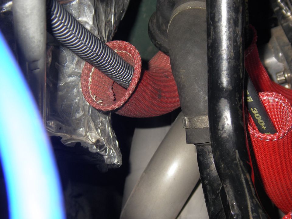 Engine bay with red protective sleeving on hoses and silver corrugated tubing