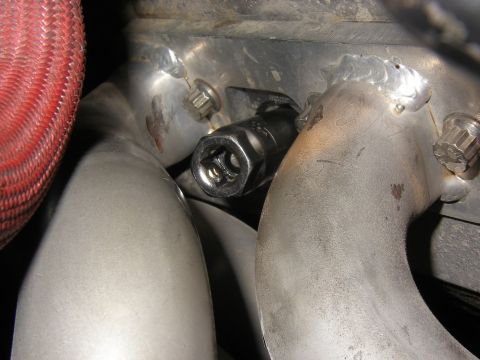 1990 Ford Bronco - Socket wrench on exhaust manifold bolt, likely during maintenance.
