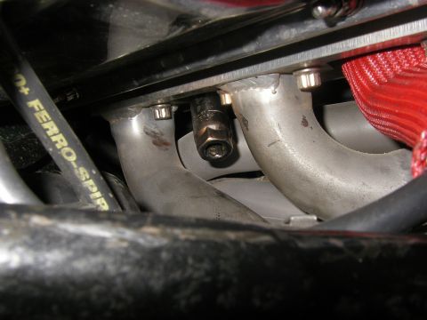 1990 Ford Bronco - A close-up view shows a spark plug being serviced within the engine compartment, near the exhaust manifold.