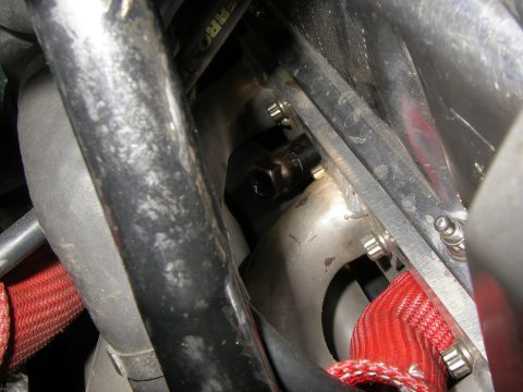 1990 Ford Bronco - A close-up view of engine components, including a bolt and a red braided hose.