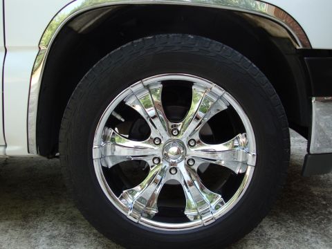 2002 Chevrolet Silverado 1500 - Close-up of a chrome wheel and tire on a white vehicle.