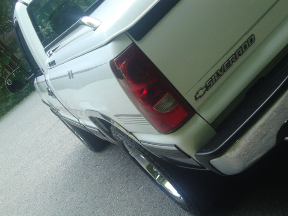White Chevrolet Silverado pickup truck rear quarter view, showing taillight, "SILVERADO" badge, and chrome bumper