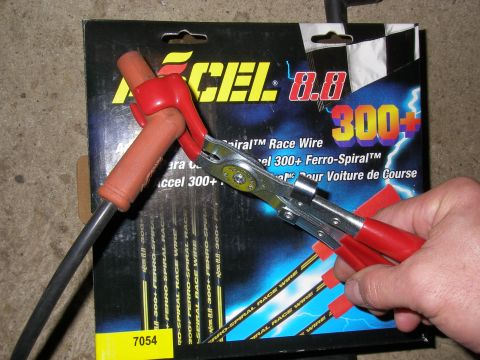 1990 Ford Bronco - A hand uses pliers to hold a spark plug wire with a red boot, in front of a package of Accel 8.8 300+ Race Wire.