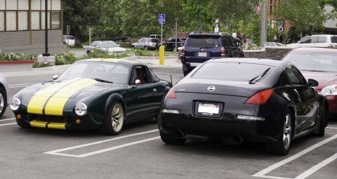 2006 Cadillac STS - Two sports cars are parked in a lot, one dark green with yellow stripes and the other black.