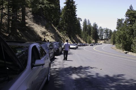 2006 Cadillac STS - A line of cars are parked on the side of a winding mountain road, with one car in the foreground having its hood open.
