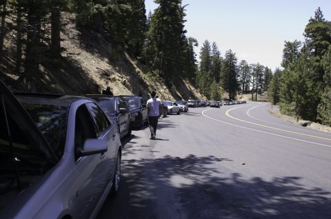2006 Cadillac STS - A long line of vehicles are parked on the shoulder of a scenic mountain road.