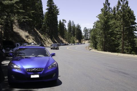 2006 Cadillac STS - A line of cars are parked along a scenic mountain road, with a blue Hyundai Genesis in the foreground.