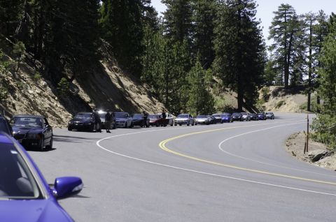 2006 Cadillac STS - A convoy of cars is parked along a winding mountain road, with a blue car in the foreground.