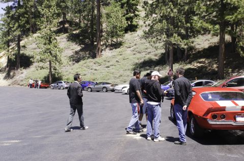 2006 Cadillac STS - Several cars are parked in a lot with people gathered around.