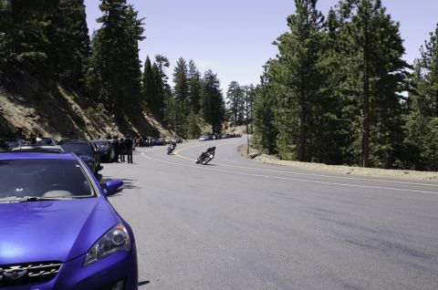 2006 Cadillac STS - Motorcycles navigate a scenic mountain road with parked cars along the shoulder.