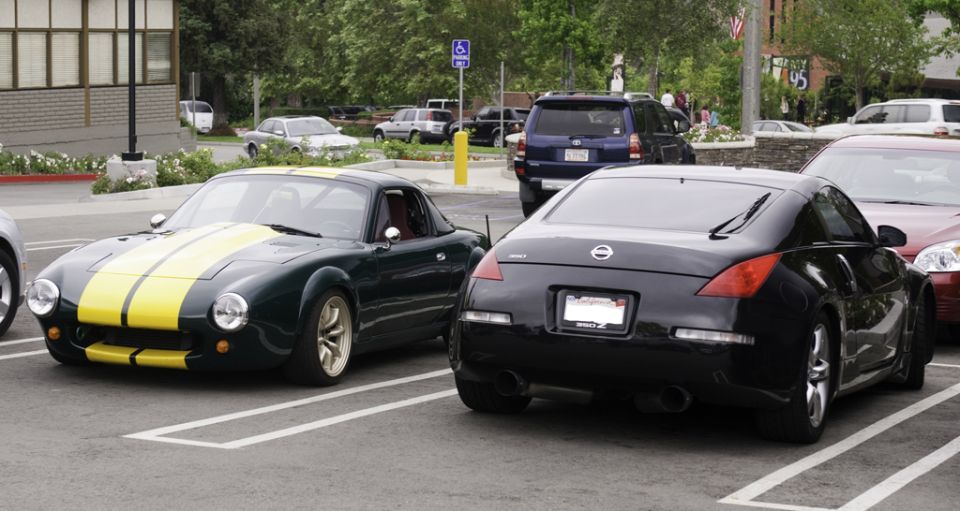 Dark green coupe with yellow racing stripes parked in a lot, front 3/4 view