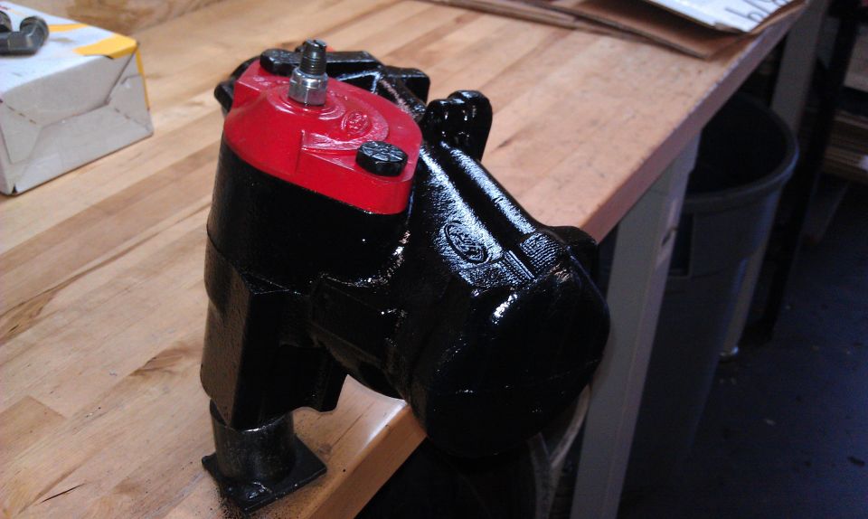 Black and red power steering gearbox on a wooden workbench