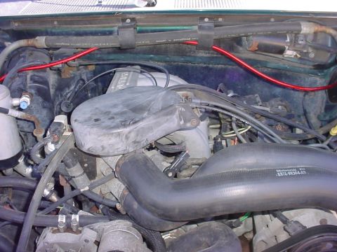 1992 Ford Bronco - Close-up of an engine bay, showing various components and wiring. A part number is visible on a hose.