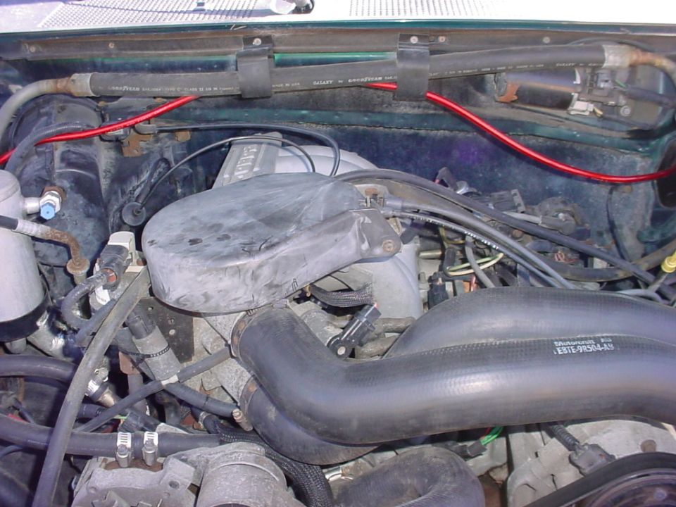 Engine bay with hoses, wiring, and intake manifold. Part number E8TE-9R504-A9 visible on a hose
