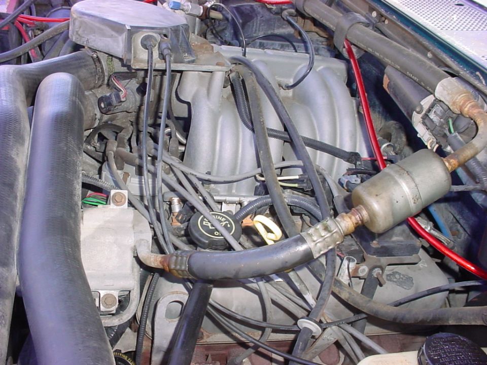 Engine bay with hoses, wires, and intake manifold visible. Oil cap reads 'Ford Motorcraft'