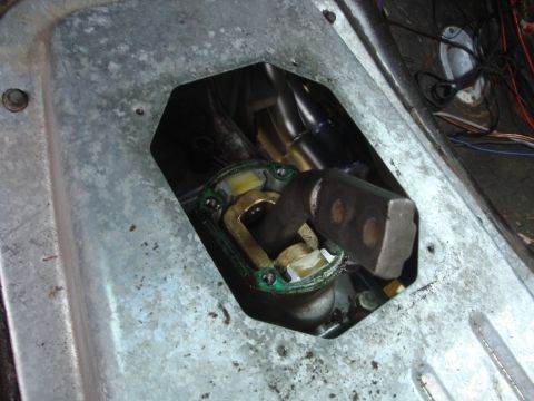 1989 Ford Bronco - The internal mechanism of a vehicle's shifter linkage is visible through an opening in the floor panel.