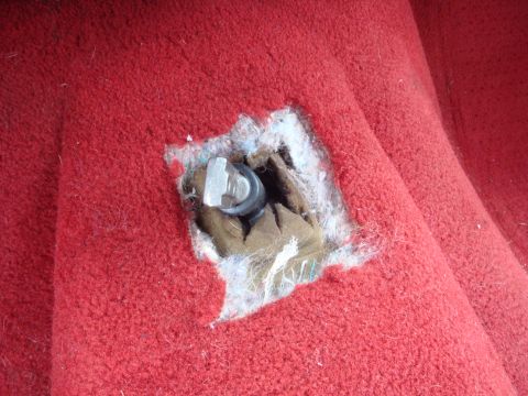 1989 Ford Bronco - Close-up of red carpet interior showing a bolt and exposed padding.