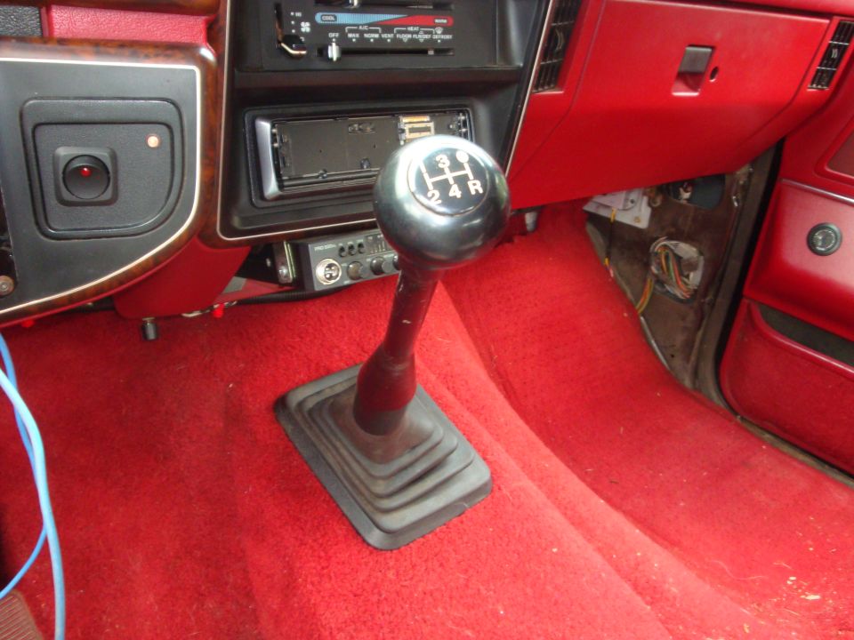 1989 Ford Bronco interior showing manual transmission shifter, radio, and red carpet