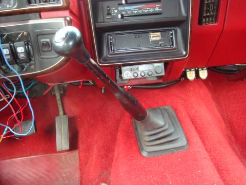 1989 Ford Bronco - The interior of a vehicle, a manual transmission shifter and various dashboard controls.