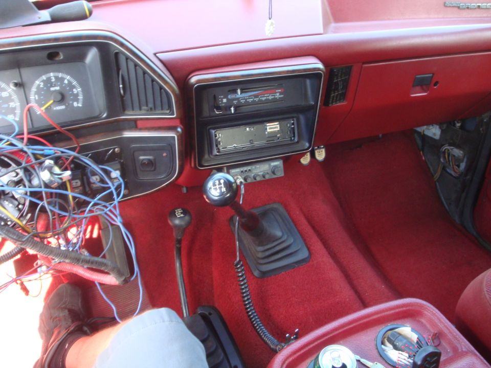 Red interior of a car with exposed wires near the dashboard and a manual transmission shifter