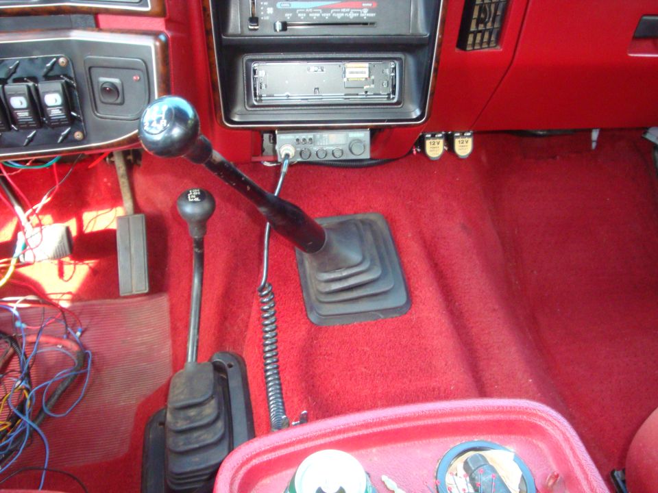 Interior view of a 1989 Ford Bronco showing the center console with two gear shifters, CB radio, and aftermarket stereo