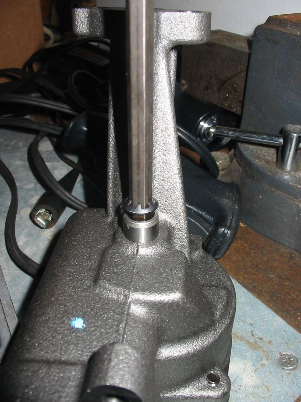 Cast metal component with hex wrench inserted into a central opening. Blue mark on surface