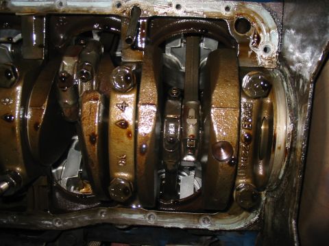 1992 Ford Bronco - Close-up view of the engine's crankshaft and connecting rods, showing internal components and some part identification marks.