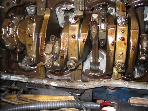1992 Ford Bronco - Close-up view of the internal engine components, specifically the crankshaft and connecting rods, covered in oil.