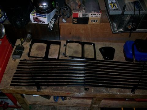 1983 Chevrolet C/K Pickup - Parts for a vehicle, including a grille and headlight bezels, are laid out on a wooden workbench.