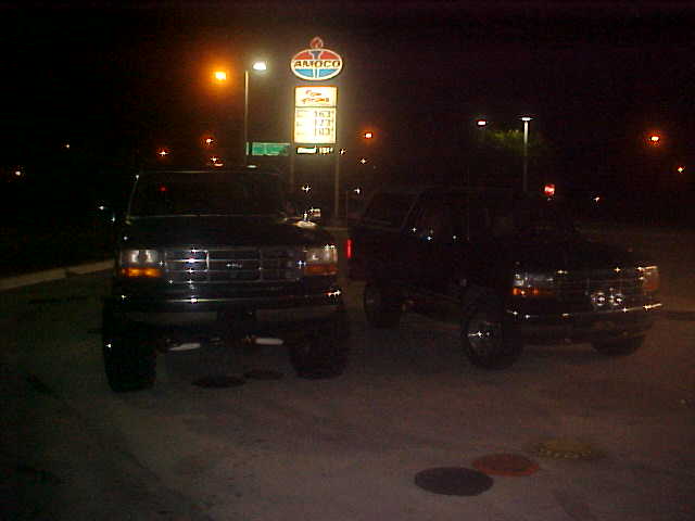 1996 Ford Bronco and another Bronco parked at an Amoco gas station at night