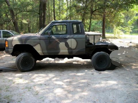 1994 Ford Explorer - This modified pickup truck features a custom flatbed and camouflage paint job, seen in a wooded area.