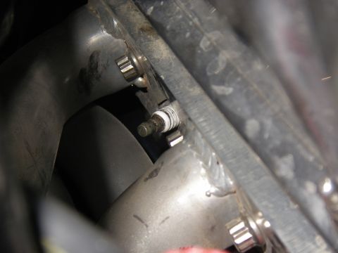 1990 Ford Bronco - Close-up view of a spark plug installed in an engine component.