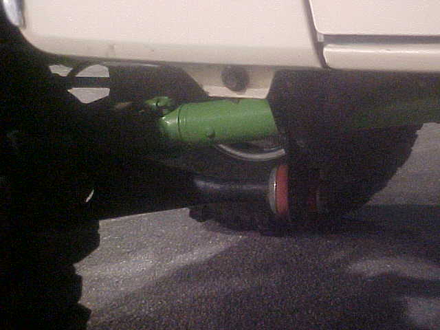 Underside view of vehicle showing green-painted axle, driveshaft and rear suspension
