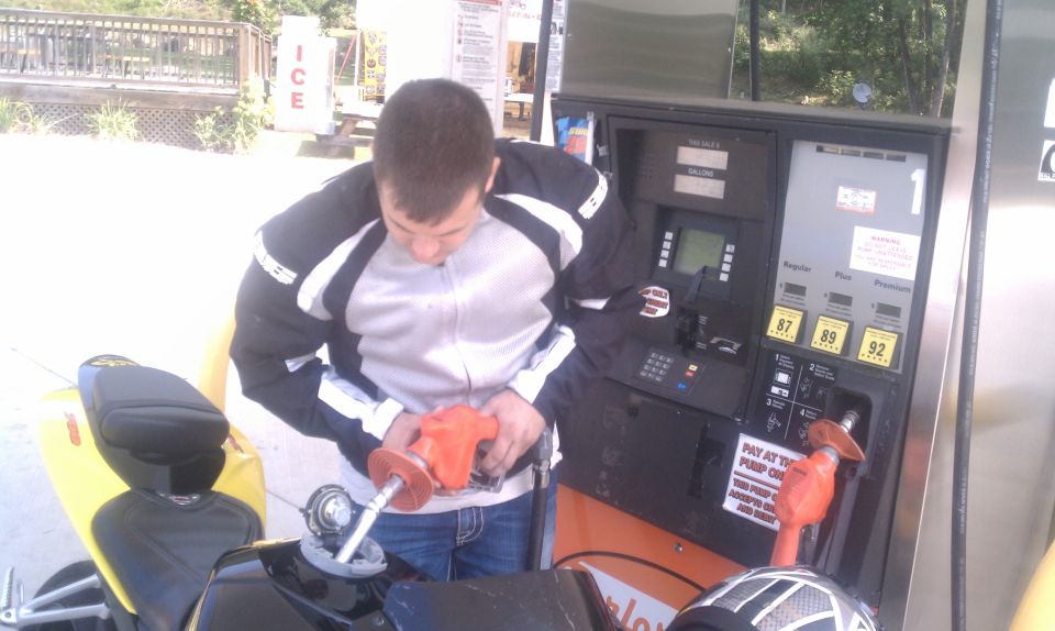 Yellow motorcycle fuel tank being filled at gas station