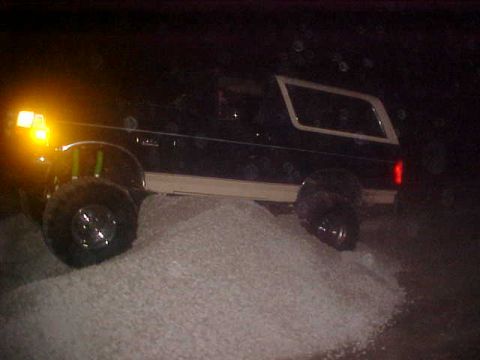 1996 Ford Bronco - A black 1996 Ford Bronco navigates a pile of white material in the dark.